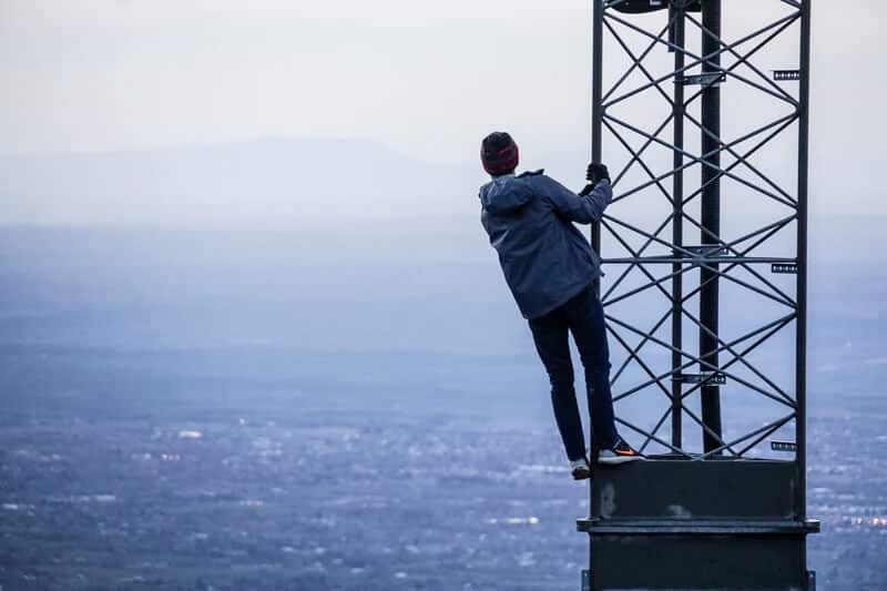 person holding onto cell tower
